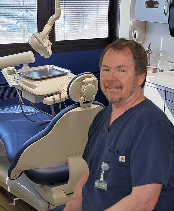 Dentist in his office surrounded by dental equipment.